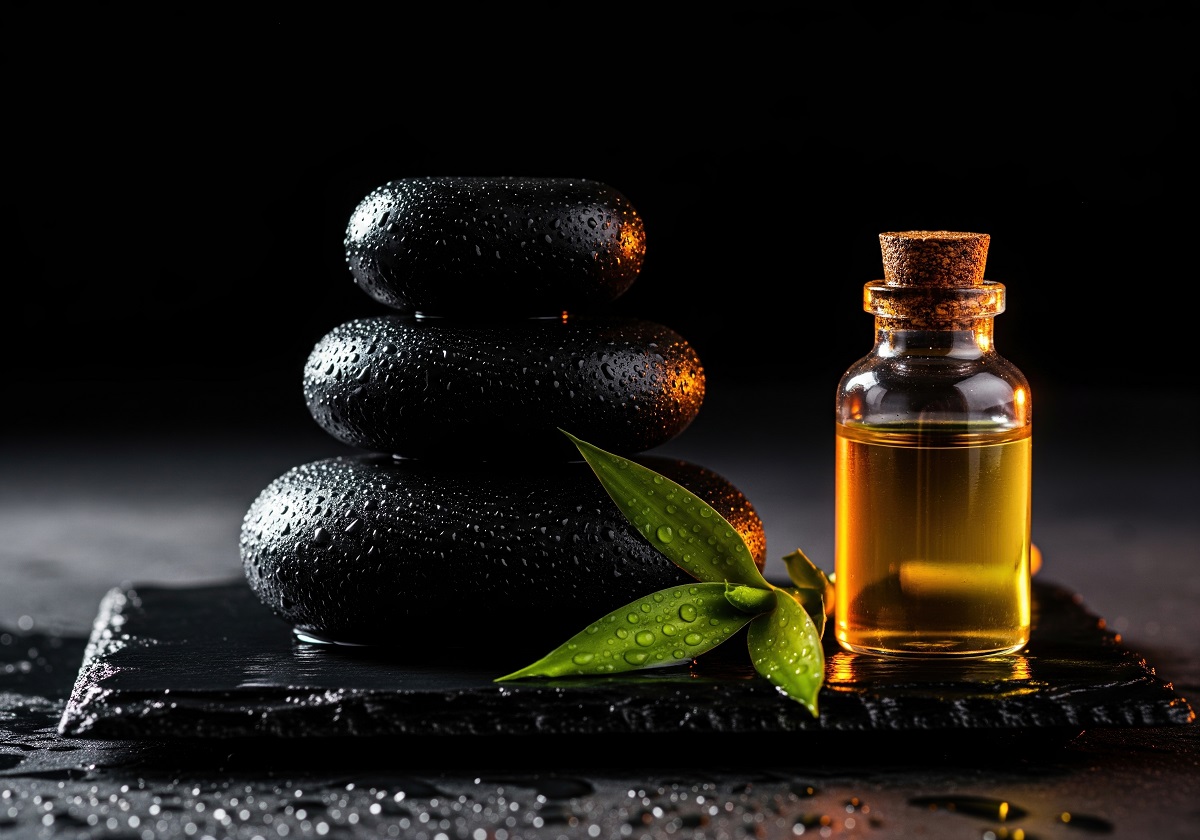 black stones stcked next to tea leaf and oil bottle used for massage therapy